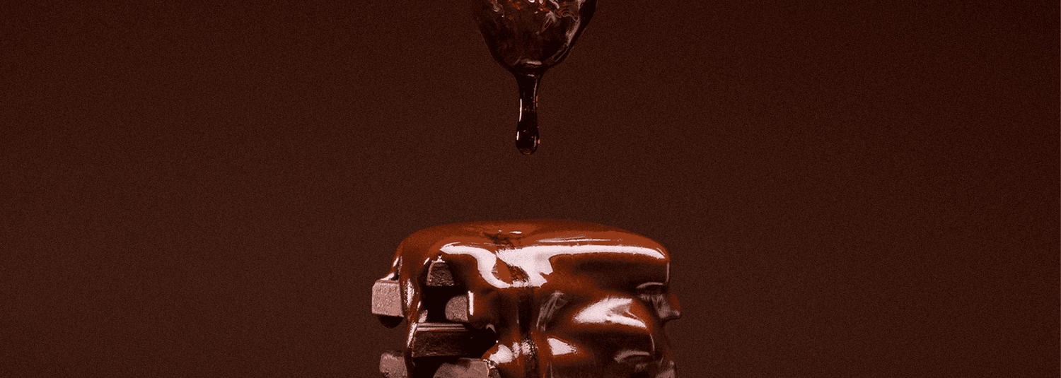 Chocolate being dripped onto a surface with a dark brown background